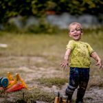 Little boy walks on a muddy road after rain